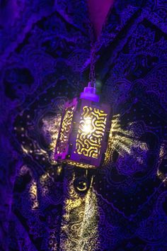 a purple lantern hanging from the side of a man's shirt with an intricate pattern on it