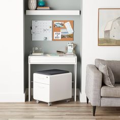 a white desk with a chair and pictures on the wall above it in a living room