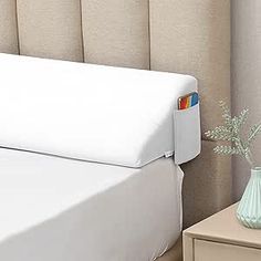 a bed with a white headboard next to a nightstand and a vase filled with flowers