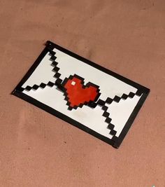 a piece of art that looks like a pixel heart on a brown surface with black and white border