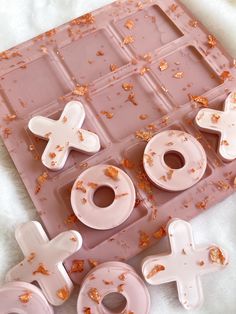 pink and white doughnuts are arranged in the shape of crosses on an ice tray