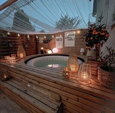 an outdoor hot tub with candles on the side and lights hanging from it's sides