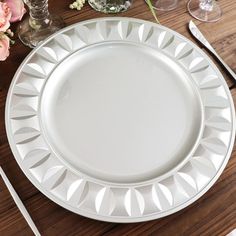 a white plate sitting on top of a wooden table next to glasses and utensils