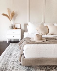 a bedroom with a bed, dresser and hat on it's headboard in front of a white paneled wall