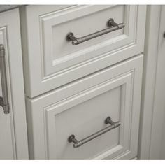 a white kitchen cabinet with handles and drawers