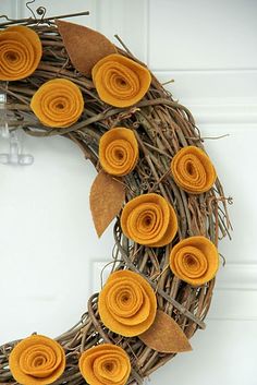 a wreath decorated with felt flowers and leaves on the front door for fall or halloween