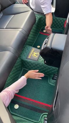 two people standing in the back seat of a car with their hands on the floor