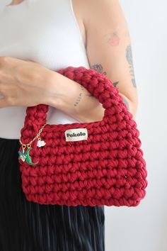 a woman holding a red crocheted purse