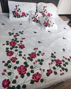 a bed with white sheets and pink flowers on it's side, along with matching pillow cases