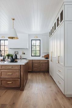 a kitchen with white walls and wooden floors, along with an island in the middle