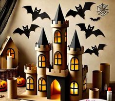 a castle made out of cardboard with bats on the wall behind it and candles in front