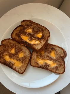 three pieces of toast with cheese on them sitting on a white plate next to a cup