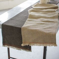 a striped table runner on top of a black and white table with a potted plant next to it