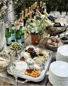 a table full of wine bottles, cheeses and crackers with plates on it