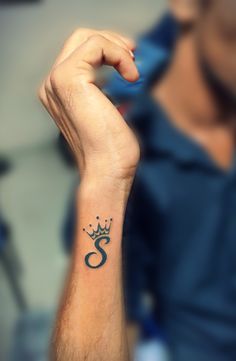 a man's arm with a crown tattoo on his left wrist and the number six