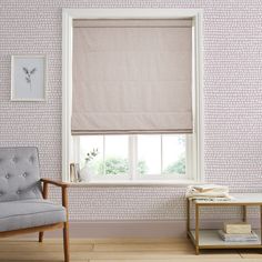 a living room with pink wallpaper and a window covered in roman blind shades on the windowsill