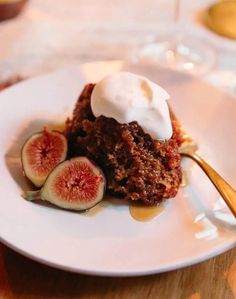 a piece of cake with whipped cream and figs on the side sitting on a white plate