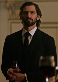 a man in a suit holding a glass of wine