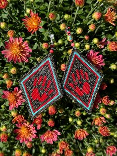 two red and blue beaded earrings sitting on top of flowers