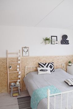 a white bed sitting next to a wooden wall in a room with pictures on the walls