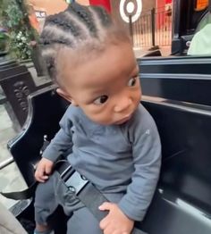 a baby sitting in the back of a truck with dreadlocks on it's head