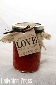 a jar filled with jam sitting on top of a white cloth covered table next to a tag