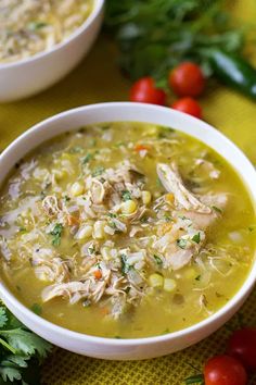 two bowls of chicken and corn soup on a yellow tablecloth with tomatoes, parsley