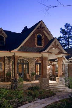 a house with stone and wood trimmings in the front yard at night time