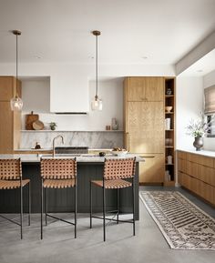 a kitchen with two bar stools next to an island in the middle of it