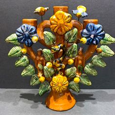 an orange vase with blue and yellow flowers in it's center, sitting on a gray surface