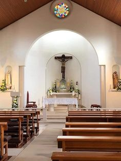 the inside of a church with pews and stained glass window above it's alter