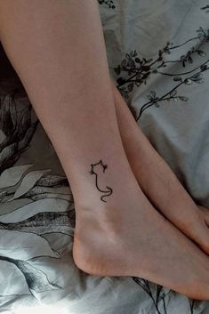 two people with tattoos on their feet laying in bed and one has a cat tattoo on the foot