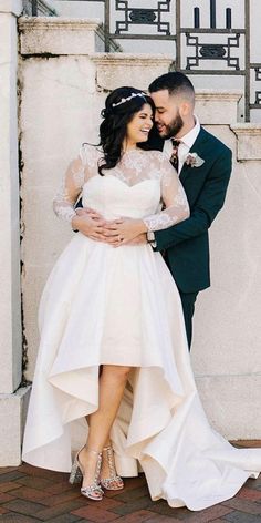 a bride and groom standing next to each other in front of a wall with columns