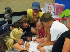 a group of young people sitting around each other in a circle on the floor together