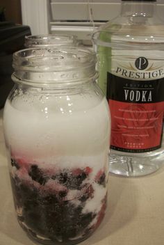 a glass jar filled with liquid next to a bottle of vodka