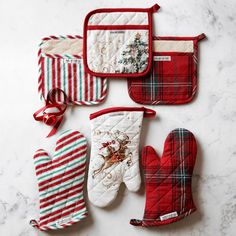 four oven mitts and two oven mitts on a marble countertop with christmas decorations