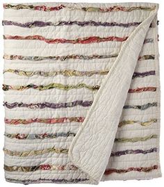 a white quilted blanket with multicolored stripes on the top and bottom half