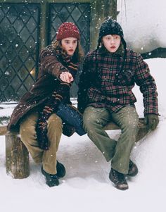 two people sitting on a bench in the snow