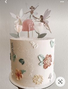 there is a cake decorated with flowers and fairy figurines on top of it