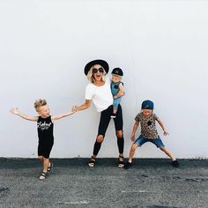 a woman and three children standing in front of a white wall with their arms outstretched