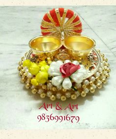 two gold bowls with flowers and pearls in them sitting on a marble surface next to each other