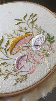 a close up of a embroidery on a piece of cloth with flowers and leaves in it