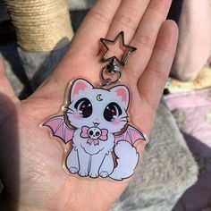 a hand holding a cat shaped keychain with a star on it's side