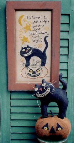 a black cat sitting on top of a potted plant next to a framed picture