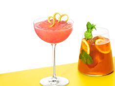 two glasses filled with drinks sitting next to each other on a yellow counter top,