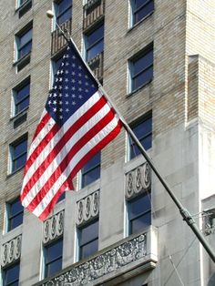 an american flag flying in front of a tall building