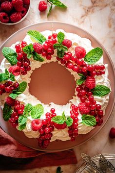 a cake decorated with berries and mints on top of a wooden board next to other decorations