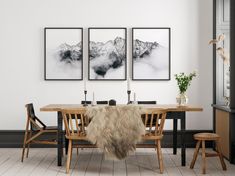 two paintings hang on the wall above a dining room table with chairs and a fur rug