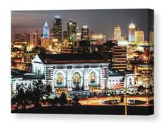 the city skyline is lit up at night, with lights on and buildings in the background