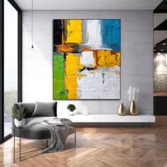 an abstract painting hangs on the wall in a modern living room with wood flooring